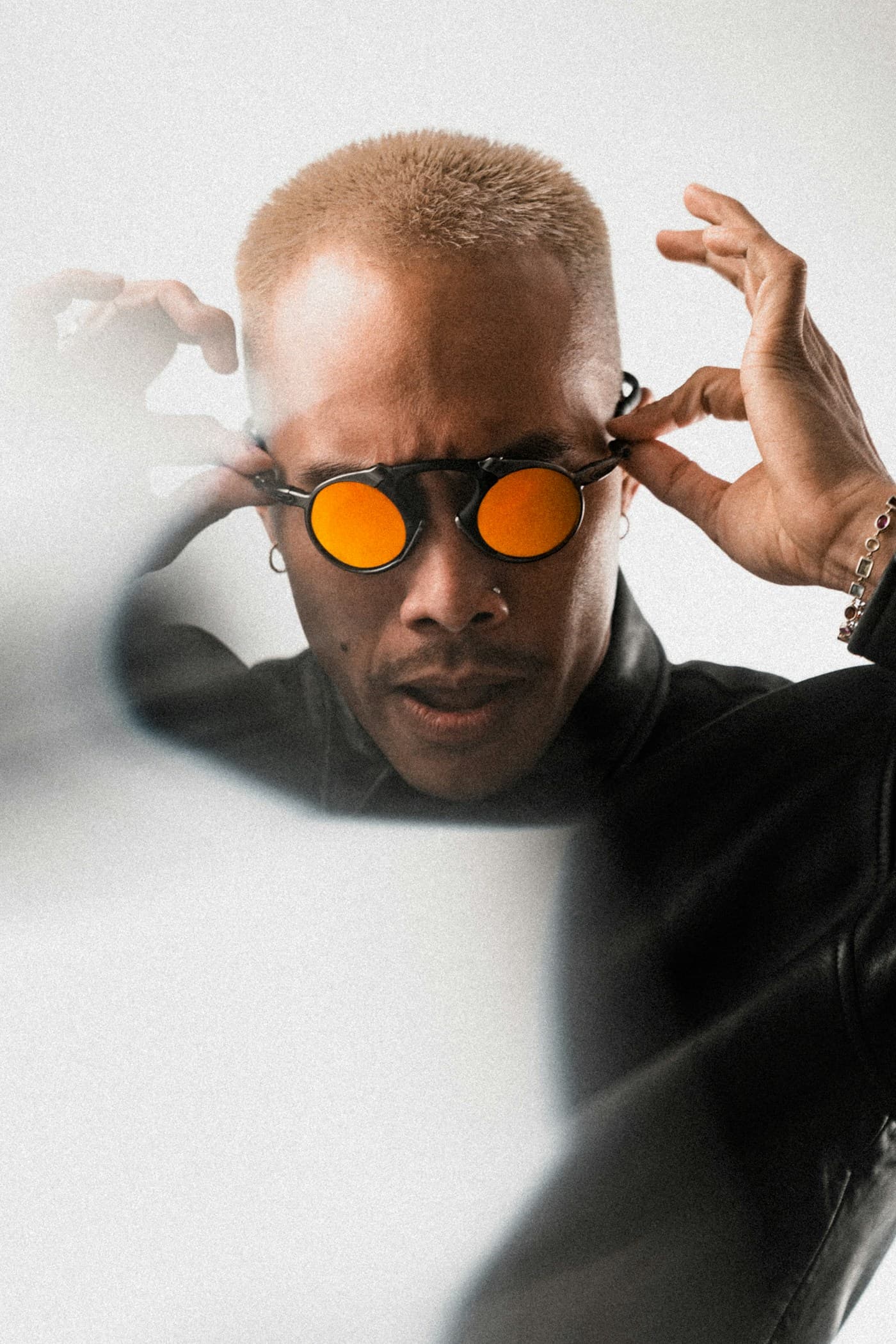 Fashion portrait of a model adjusting orange sunglasses.