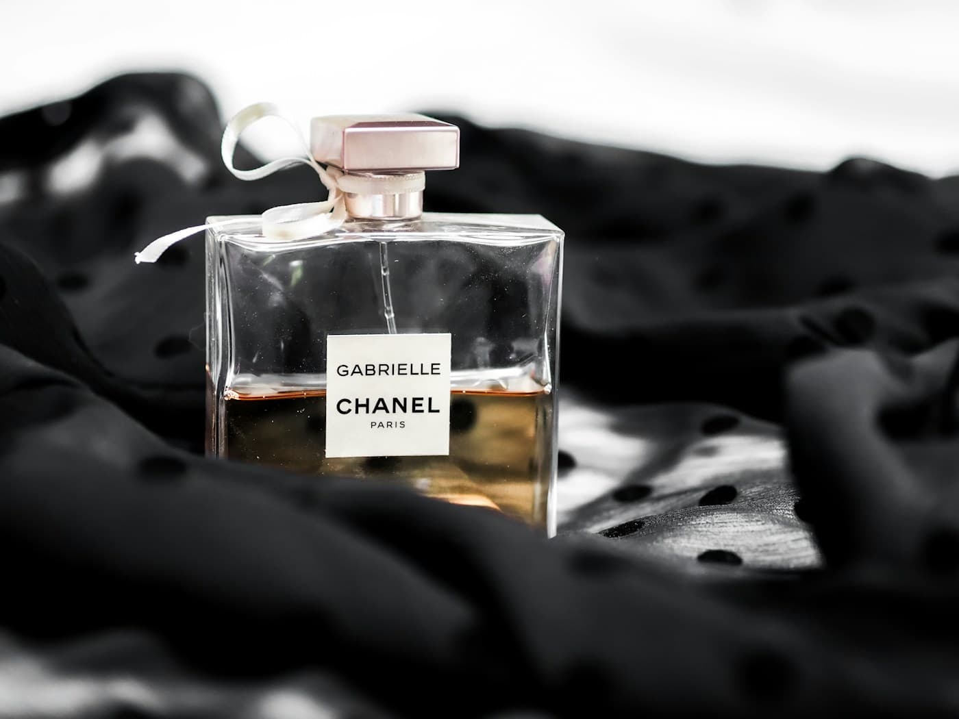 Clear perfume bottle placed on black and white textile.